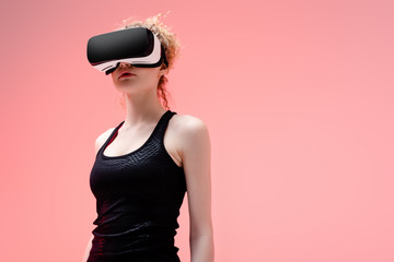 young woman in in sportswear and virtual reality headset on pink