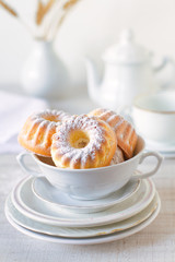 
Mini bundt cakes with icing sugar on a stack of white plates