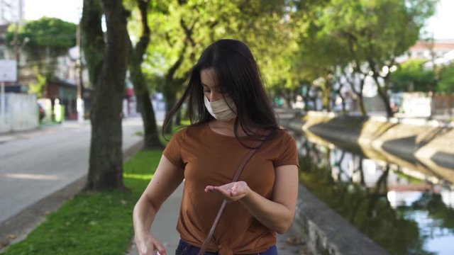 woman wearing mask sanitize hands walking on the street dolly shot in slowmotion. pandemic coronavirus concept
