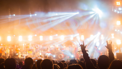 crowd at concert - summer music festival in front of bright stage lights. Dark background, smoke, concert spotlights.people dancing and having fun in summer festival