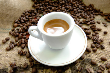 italian espresso coffee cup on a jute canvas and with coffee beans