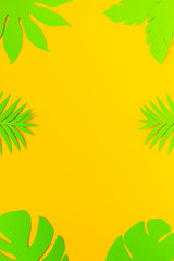 Fototapeta na wymiar Summer backgroud. Green palm tree leaves on yellow backdrop. Paper art. Top view. Flat lay. Copyspace. Empty. Vertical layout