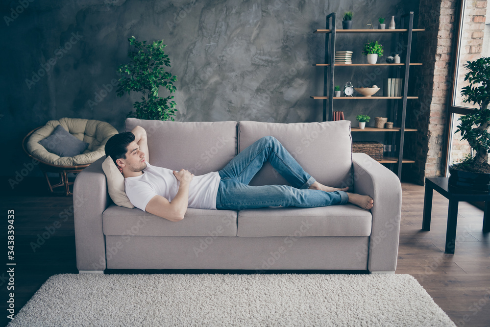 Sticker Profile side view portrait of his he nice attractive guy lying on divan resting free time pause break at modern industrial loft brick interior style living-room