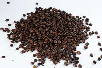 Coffee beans laid out on a white background with a basket