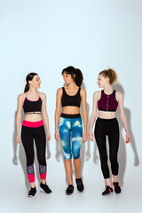 Fototapeta premium multicultural and happy women in sportswear walking on white