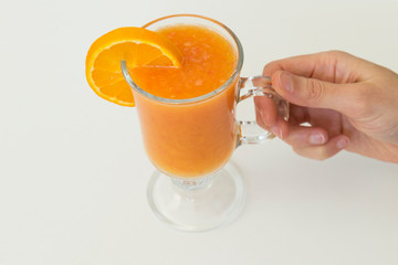 A glass of natural orange juice on wooden floor.