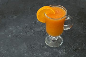 A glass of natural orange juice on wooden floor.