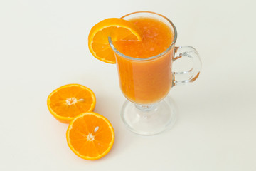 A glass of natural orange juice on wooden floor.