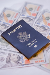 One single blue American passport on top of a pile of US dollars