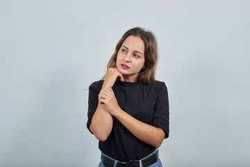 Young brunette lady in black t-shirt on grey background cute beautiful woman gently touches her hand