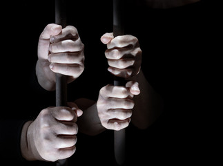 Two people are in prison. Her hands cling to the bars.