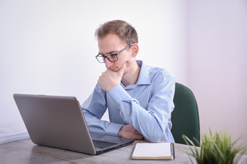 Portrait of young business man sitting at his desk desktop laptop technology in the office.Internet marketing, finance, business concept