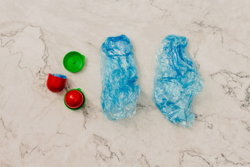 Two medical blue shoe covers in individual capsules with green\red colored caps. Disposable shoe covers. Protection concept.