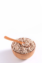 Dry raw brown tapioca pearls in a wooden bowl with spoon isolated on white background, close up, ingredient of making bubble boba milk tea.