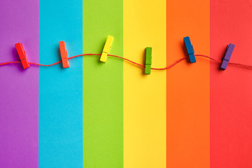 rainbow colored wooden clothespins on lgbt flag background.