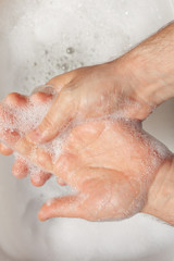 a man washes his hands over water with foam