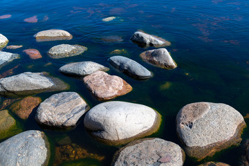 Fototapeta na wymiar Stones in clear blue lake water. Lake Ladoga, Russia.