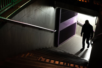 Silhouette of a suspicious man. Man up the stairs of the subway. - obrazy, fototapety, plakaty