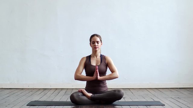 Young and fit woman practicing yoga indoor in the class. Stretching exercise in the day light. Sport, fitness, health care and lifestyle.