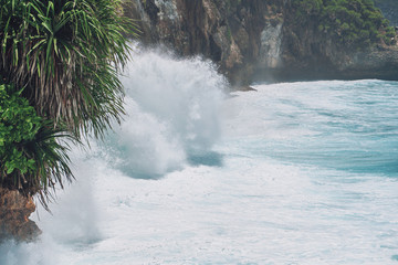 Photo of large waves crashing into large rocks on Nusa Penida