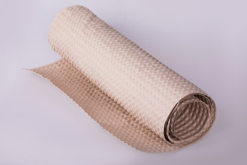 Roll of beige wrapping paper on a white background. It is used to prevent something from bumping, recyclable material, of roll of brown corrugated cardboard, space for text. recyclable material
