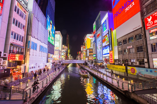 Osaka, Japan - April 1, 2017: Tourist boat cruise pass Dotonburi district which is known for shopping street, entertainment, food and Gulico running man sign.
