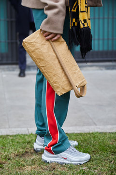 Man with gray Nike sneakers and green trousers with red stripe and beige paper bag on January 15, 2018 in Milan, Italy