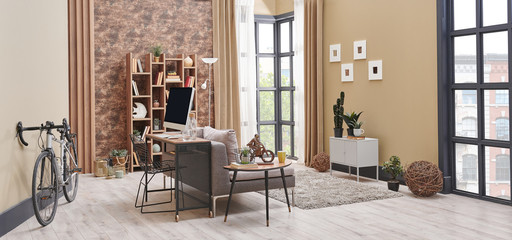 Brown living room interior decoration with wallpaper detail, grey sofa, wooden coffee table and working desk in the living room.