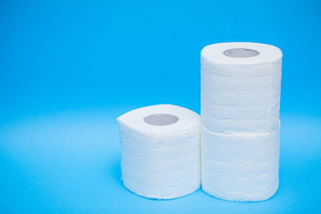 Rolls of white toilet paper on blue background.