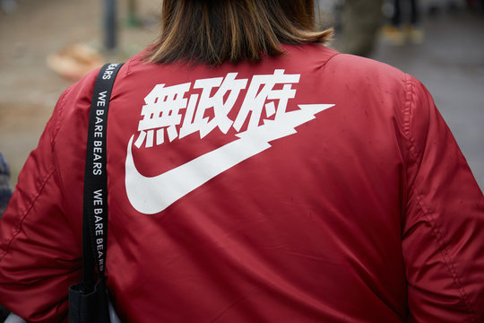 Woman with red bomber jacket with white Nike japanese logo on February 22, 2018 in Milan, Italy