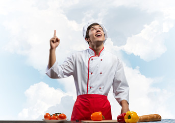 Young male chef standing near cooking table