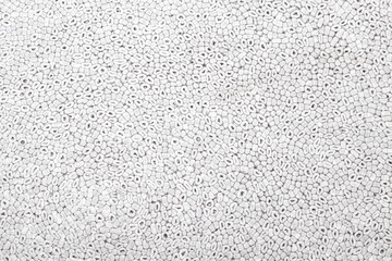Obraz premium Background of gray color with a pattern of oval and round parts of polystyrene similar to sea pebbles pressed and used to trim or protect fragile parts close-up. Design panel or building material.