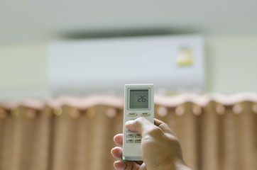 Close up hands press the remote control with air conditioner, energy-saving concept