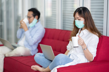 Asia women and Friend sitting on sofa and social distancing to work from home