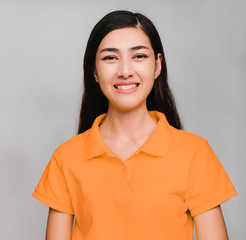 young beautiful asian woman,long black hair, wore orange t shirt,smile on gray background