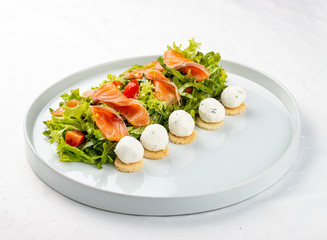 Salmon salad with cheese balls on a white plate