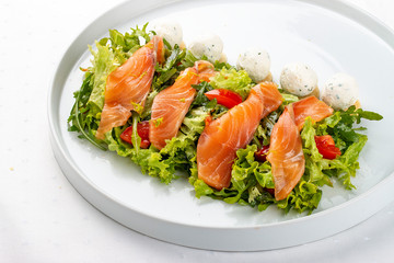 Salmon salad with cheese balls on a white plate