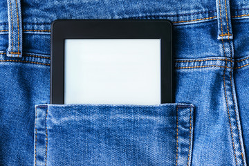 A modern black electronic book with a blank screen in the back pocket of bright blue jeans. Mockup...