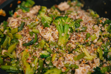 Ready buckwheat in a dark cup with vegetables. Broccoli and young beans in buckwheat. Slavic recipe