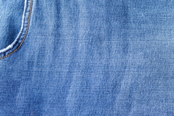 Bright blue jeans fabric texture. Denim background with pocket in the corner. Closeup view