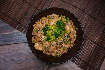 Ready buckwheat in a dark cup with vegetables. Broccoli and young beans in buckwheat. Slavic recipe
