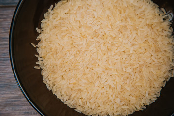 Rice in a dark cup. Ingredients for the dish. On wooden background