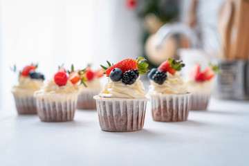 Fresh, delicious cupcakes with yogurt cream and fresh berries. Blur background.