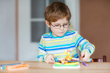 Smiling preschool kid boy having fun with dough, colorful modeling compound clay. Creative leisure with children. during corona virus quarantine staying at home. Shelter in place, lockdown concept,