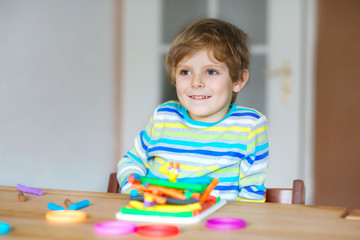 Smiling preschool kid boy having fun with dough, colorful modeling compound clay. Creative leisure with children. during corona virus quarantine staying at home. Shelter in place, lockdown concept,