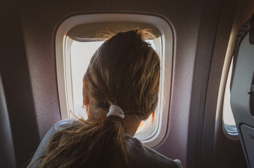 Fototapeta na wymiar Girl is looking to window airplane.