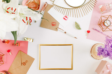 Horizontal golden blank frame on a desktop of a student girl. Creative colorful female desktop with smartphone, golden mirror, gifts, candlestick, flowers, colorful notebooks, golden clips on white