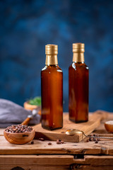 Two bottles of olive oil with bowl of olives and salad on wooden board