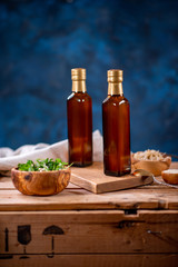Fototapeta na wymiar Two bottles of olive oil with bowl of olives and salad on wooden board