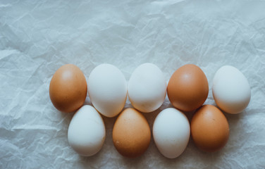 Fresh raw white and brown farm chicken eggs on white paper Healthy food top view